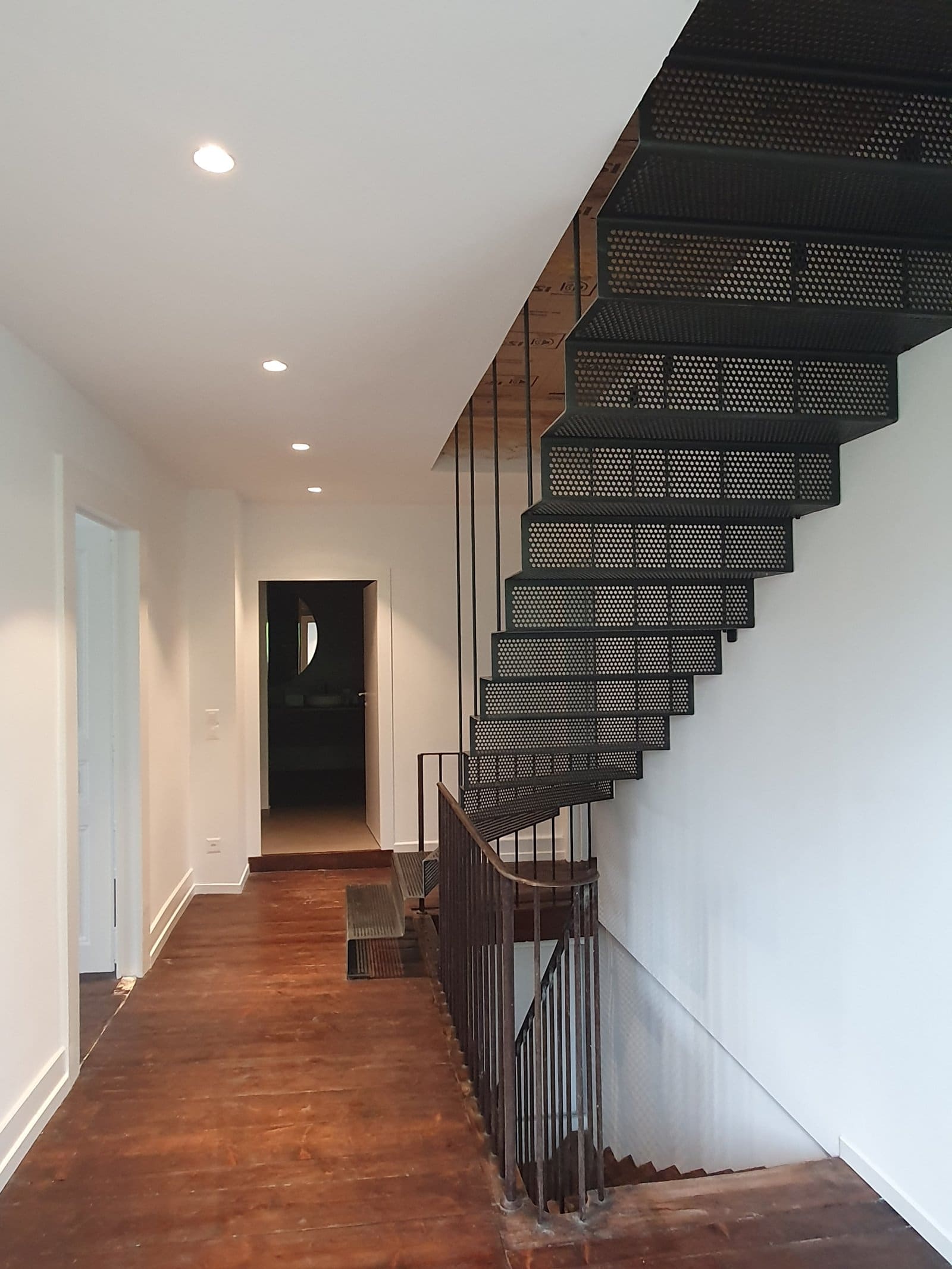 Escalier métal perforé suspendu maison de village — vue couloir vers les chambres
