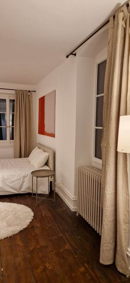 Chambre maison de village — planchers reteintés, rideaux lin, tableau