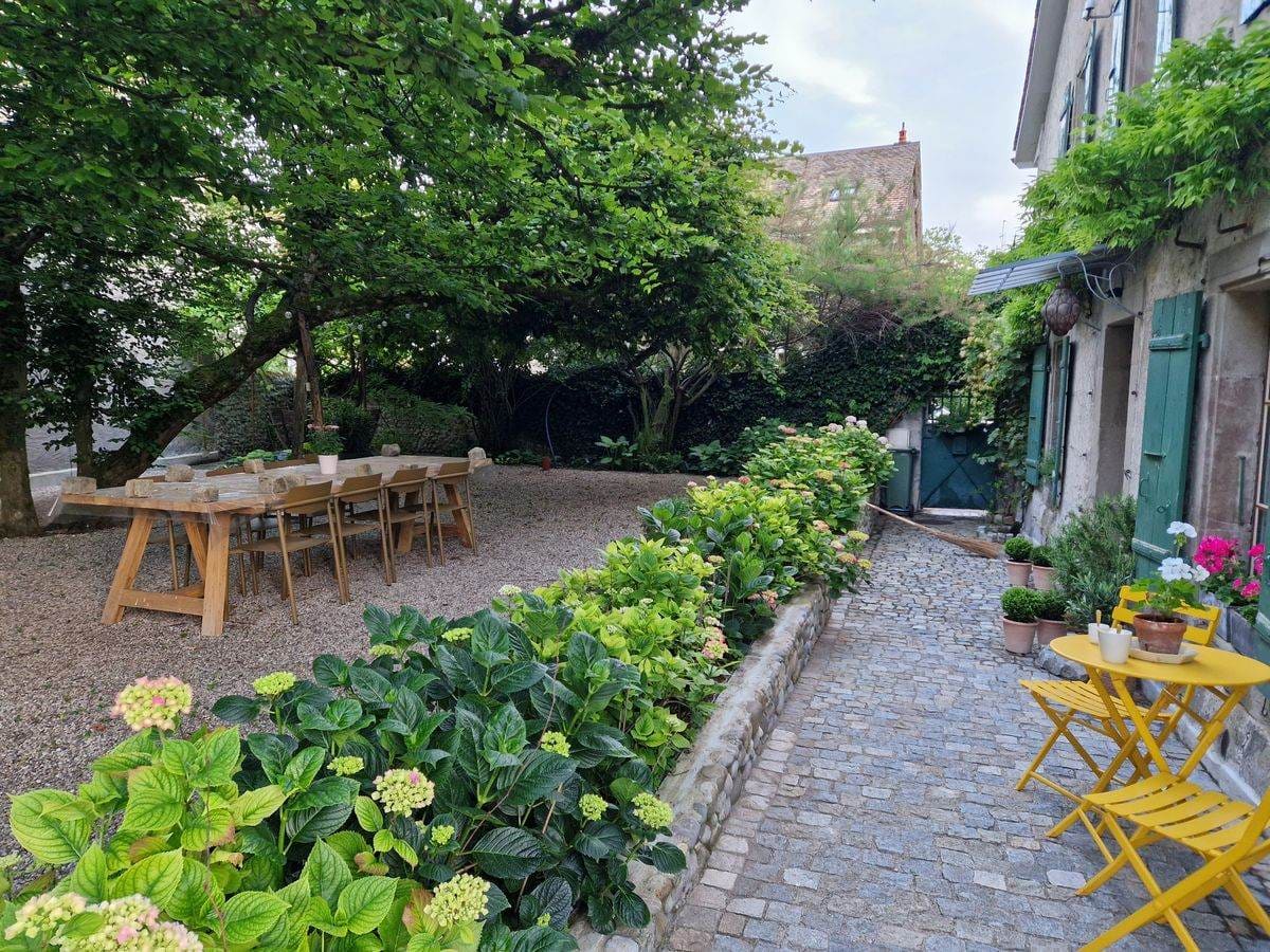 Cour — grande table bois, hortensias, volets verts